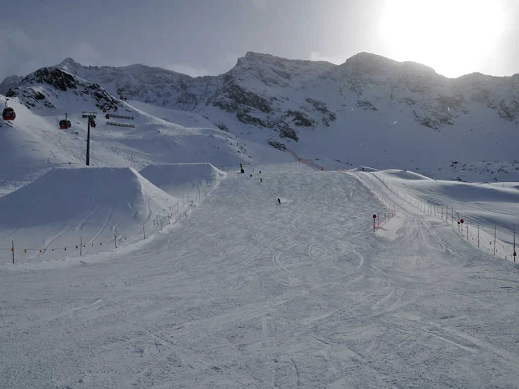 Blick auf eine breite Piste unterhalb eines Grats.